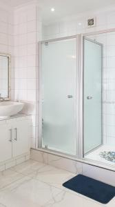a bathroom with a glass shower and a sink at Seaside Riviera in Cape Town +12 photos