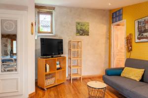 a living room with a couch and a tv at Gîte L'Atelier in Saint Martin sur Lavezon
