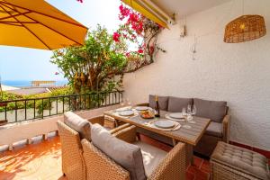 d'une table à manger avec des chaises et un parasol sur le balcon. dans l'établissement Casa Mia in Nerja - Take Care Malaga, à El Molino
