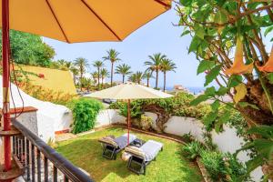 - un balcon avec un parasol, des chaises et l'océan dans l'établissement Casa Mia in Nerja - Take Care Malaga, à El Molino