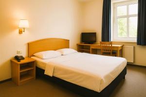 a bedroom with a bed and a desk and a television at LA MAISON DU NORD - Hotel Garni in Cuxhaven