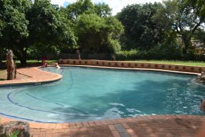 a large swimming pool in a yard with trees at Kruger Yebo Safari Tents-Stay Inside Kruger in Skukuza