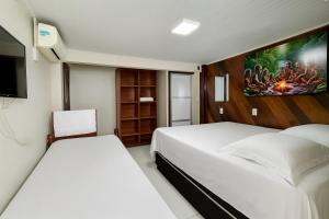a bedroom with two beds and a flat screen tv at Hotel COP 30 in Belém