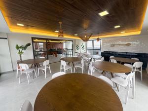 restauracja z drewnianymi stołami i białymi krzesłami w obiekcie Season Samart Flats by BLU stay w mieście Porto de Galinhas