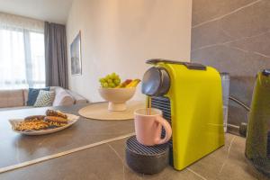 żółty ekspres do kawy stojący na stole z talerzem owoców w obiekcie Azur Alegria Studio by RV Apartments - free parking & pool w miejscowości Sweti Konstantin i Sweta Elena +60 zdjęć