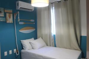 un letto in una camera con una parete blu e una finestra di Mer Bleue du Français a Marechal Deodoro Altre 21 foto