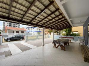 un patio coperto con un tavolo e una panca di Cód 129 - Casa aconchegante com sinuca a 300m do mar a Governador Celso Ramos
