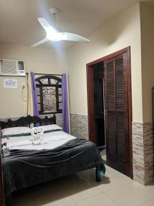 Un dormitorio con una cama y un ventilador de techo. en Recanto do sol, en Mangaratiba
