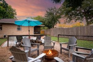 Un grupo de sillas alrededor de una fogata con una sombrilla. en Memories on Mulberry- Hot Tub Game Room Fire Pit, en Fredericksburg