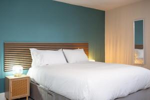- une chambre avec un grand lit blanc et un mur bleu dans l'établissement Livingston Retreat 4bed Home Wi-Fi Parking, à Uphall 13 autres photos