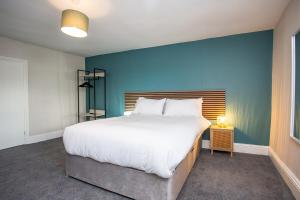 une chambre avec un grand lit avec un mur bleu dans l'établissement Livingston Retreat 4bed Home Wi-Fi Parking, à Uphall
