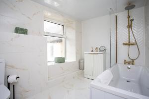 une salle de bain blanche avec une baignoire et un lavabo dans l'établissement Livingston Retreat 4bed Home Wi-Fi Parking, à Uphall