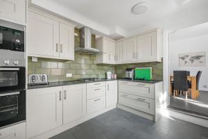a white kitchen with white cabinets and black appliances at Contractors - Businesses - Families - Long term Stays - Free parking in Thornton Heath +9 photos