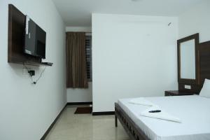 a bedroom with a bed and a flat screen tv at Hotel Aranmanai in Coimbatore