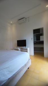 ein weißes Schlafzimmer mit Bett und Flachbildfernseher in der Unterkunft D'Villa in Uluwatu