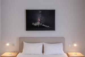 a picture of the universe above a bed with two lamps at White & Stars in Athens