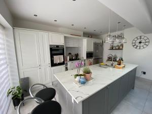 une cuisine avec des placards blancs et une grande île avec des chaises dans l'établissement Modern home in Cardiff City Centre, à Cardiff