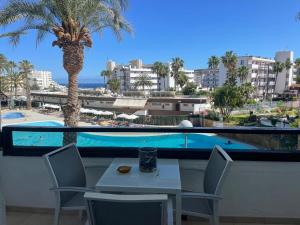 a table and chairs on a balcony with a palm tree at Nice Apartment 1210 In Central Area in San Bartolomé de Tirajana