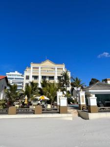 ein großes weißes Gebäude mit Palmen davor in der Unterkunft Golfinhos Apart hotel - apto térreo na praia com café da manhã! in Florianópolis