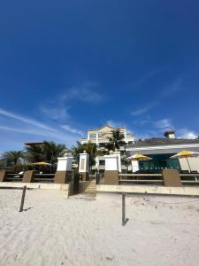 ein Gebäude am Strand neben einem Sandstrand in der Unterkunft Golfinhos Apart hotel - apto térreo na praia com café da manhã! in Florianópolis