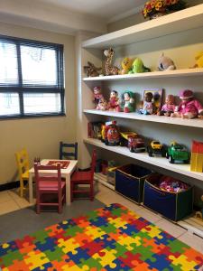Zimmer mit einem Tisch und Regalen mit Spielzeug in der Unterkunft Golfinhos Apart hotel - apto térreo na praia com café da manhã! in Florianópolis