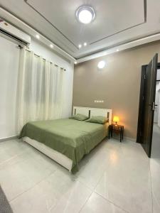 a bedroom with a large bed with a green blanket at Appartement Chic et Moderne Quartier Djidjolé in Lomé