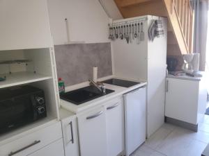 a kitchen with white cabinets and a sink and a microwave at La Maison Defanny - 2 in Muides-sur-Loire +9 photos