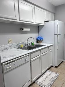 バトンルージュにあるModern Condo in the Center of BRのシンクと冷蔵庫を備えた白いキッチン
