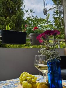 a table with a glass of white wine and flowers at Apartment am Waldrand mit Einzelgarage, Nähe City, Messe & Flughafen in Leinfelden-Echterdingen