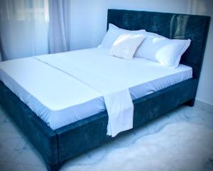 a bed with white sheets and pillows in a room at Salsa Holiday apartments in Diani Beach