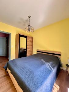 a bedroom with a blue bed and a yellow wall at Zoo Arena Stay Free Parking in Łódź