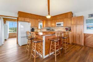a kitchen with wooden cabinets and a island with bar stools at 7142 - Sea 'N Sound in Nags Head