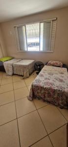 a bedroom with two beds and a window at Casa da Jussara in Itaperuna