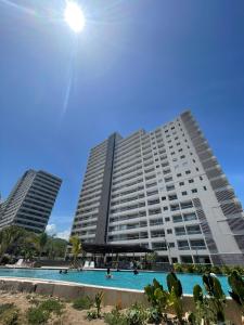 a large building with a swimming pool in front of it at Modern apartment with direct ocean view in Simón Bolivar