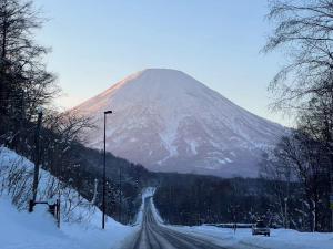 a snow covered mountain with a road in front of it at JY Snow in Kutchan