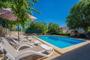 une piscine avec des chaises longues et un parasol dans l'établissement Kutić in Štokovci (Haus für 10-15 Personen), à Svetvinčenat