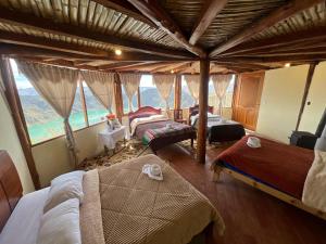 a bedroom with two beds and a large window at Urku Ñan Quilotoa in Sigchos