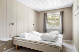 ein Schlafzimmer mit einem Bett mit weißer Bettwäsche und einem Fenster in der Unterkunft 3716 Nexø - Granvej 12 in Snogebæk