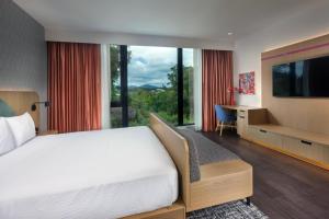 a bedroom with a bed and a desk and a large window at The Artful Way Hotel in Asheville