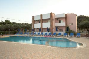 a swimming pool with blue chairs and a building at Old Windmill Studios in Faliraki