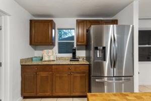 a kitchen with a stainless steel refrigerator and wooden cabinets at St Petersburg Private Villa with Pool Gym Grill Self Check-In in St Petersburg