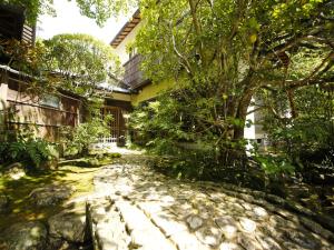 un camino de piedra frente a una casa con un árbol en Hashinoya Bekkan Ransui en Kobe