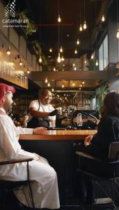 a woman sitting at a bar in a restaurant at Hive Stayz - 1 Bedroom in Catamaran Tower in Sanābis