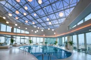 a pool in a building with a glass ceiling at Hive Stayz - 1 Bedroom Canal Harbor Row in Manama