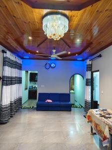 a living room with a blue couch and a chandelier at TR Rest House in Trincomalee +12 photos