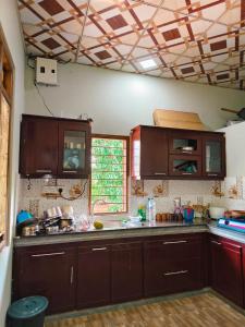 a kitchen with dark wood cabinets and a window at TR Rest House in Trincomalee
