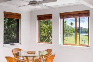 une salle à manger avec une table en verre et des fenêtres dans l'établissement Lil Nauti, à Brunswick Heads 13 autres photos
