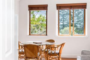 une salle à manger avec une table et des chaises et deux fenêtres dans l'établissement Lil Nauti, à Brunswick Heads