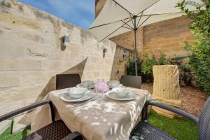 a table with an umbrella in a yard at Casa Elena, Private Garden, Office,1 Minute to the Sea by Haven & Keys Malta in Sliema