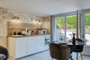 a kitchen with white cabinets and a table at L'Escapade Enchantée - Spa, Cheminée et Cinéma in Tournedos-Bois-Hubert